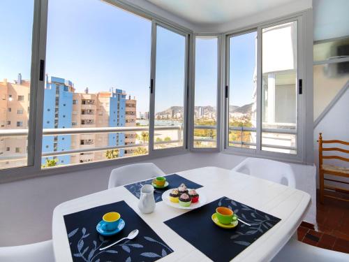 einen weißen Tisch mit zwei Teller Essen drauf in einem Zimmer mit Fenstern in der Unterkunft Apartment Aguamarina-1 by Interhome in Calpe