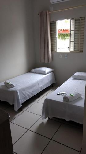 a bedroom with two beds and a window at Hotel Vale do Sol in Votuporanga