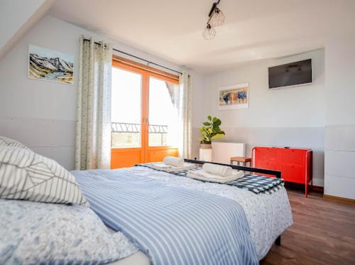 a bedroom with a blue and white bed and a window at Atlas Chmur Apartament in Biały Dunajec