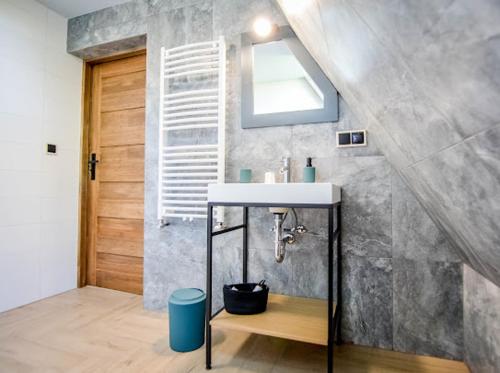 a bathroom with a sink and a mirror and a door at Atlas Chmur Apartament in Biały Dunajec