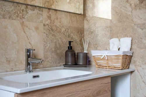 a bathroom with a sink and a basket of towels at Zephir Apartments in Brindisi