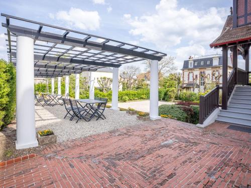 un patio avec une table et des chaises sous une pergola dans l'établissement Apartment La Pergola by Interhome, à Cabourg