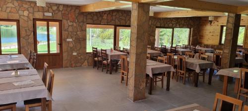 a restaurant with tables and chairs and windows at Apartmani JEZERO in Žabljak