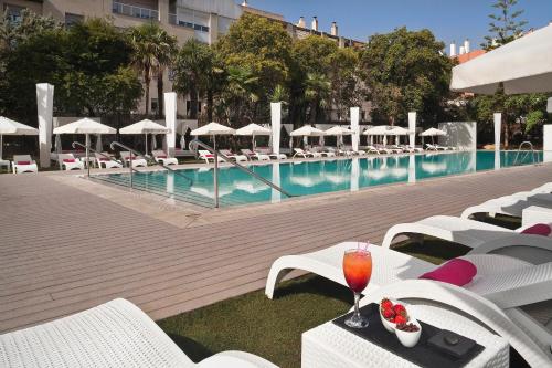 a pool with white chairs and a drink on a table at Melia Lebreros in Seville