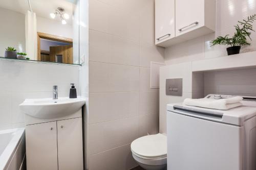 een witte badkamer met een toilet en een wastafel bij Prime Home PARKOWY in Gdynia