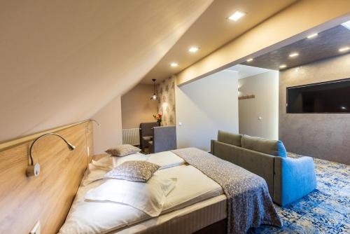 Hotel Tusnad في بايلي توشناد: غرفة نوم بسرير واريكة وتلفزيون