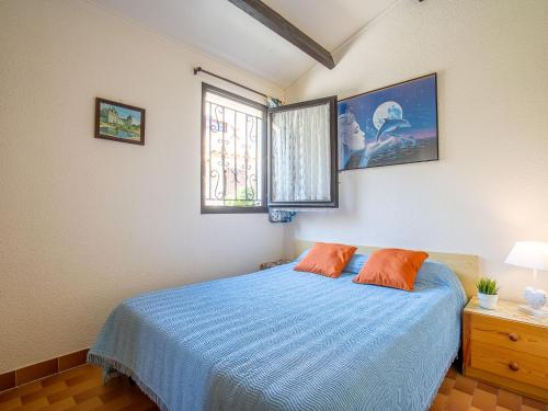 una camera con letto blu e 2 cuscini arancioni di Holiday Home Les Maisons de la Plage-1 by Interhome a Le Grau-du-Roi