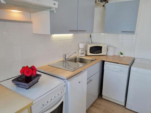 une cuisine blanche avec un évier et un micro-ondes dans l'établissement Apartment Le Petit Robinson-5 by Interhome, à La Richardais