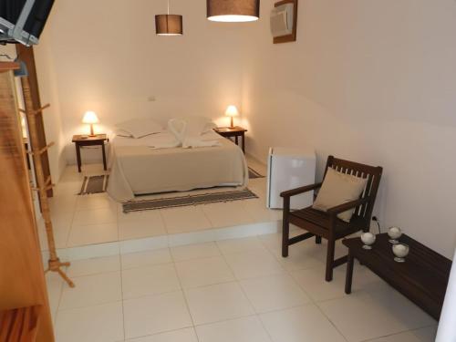 1 dormitorio con cama, silla y luces en Corsário Hotel, en Ubatuba