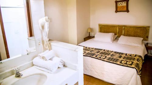 bagno con letto e lavandino con asciugamani di Corsário Hotel a Ubatuba