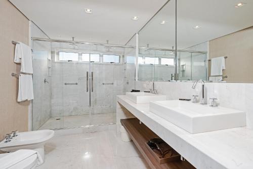 a white bathroom with two sinks and a shower at Slaviero Curitiba Centro in Curitiba