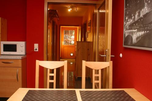 a dining room with two chairs and a red wall at Ferienwohnung Sabine in Hornberg