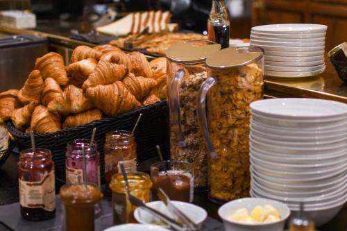 Una mesa con una cesta de pasteles y platos de comida. en Hotel Parister Piscine & Spa, en París