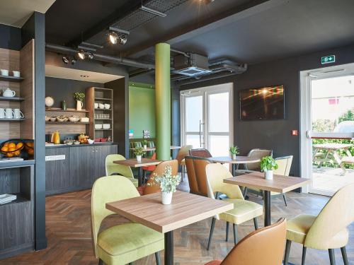 a restaurant with wooden tables and yellow chairs at Kyriad Rouen Sud - Val de Reuil in Val de Reuil