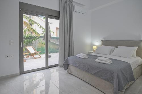 a white bedroom with a bed and a sliding glass door at Moka Apartments in Chania Town