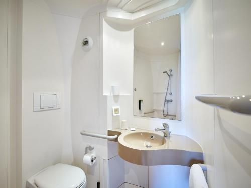 a white bathroom with a sink and a toilet at Kyriad Rouen Sud - Val de Reuil in Val de Reuil