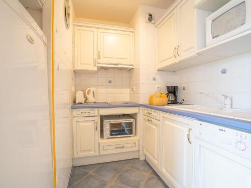 une cuisine avec des armoires blanches, un évier et un micro-ondes dans l'établissement Apartment Terrasses de la Baronnie-4 by Interhome, au Grau-du-Roi