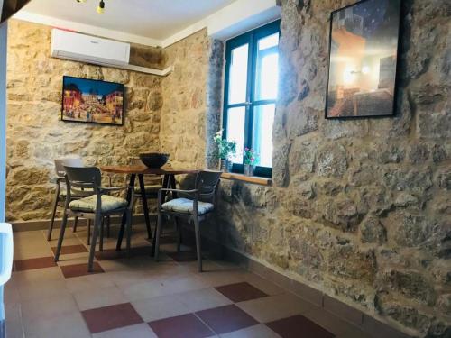 a dining room with a table and chairs against a stone wall at Stone house Saint Michael in Košute