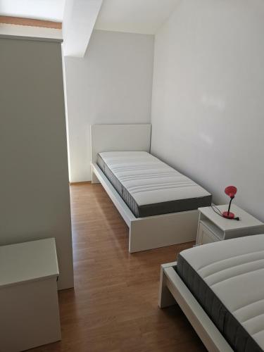 a white room with two beds and a table at Apartman Katarina Promajna in Promajna