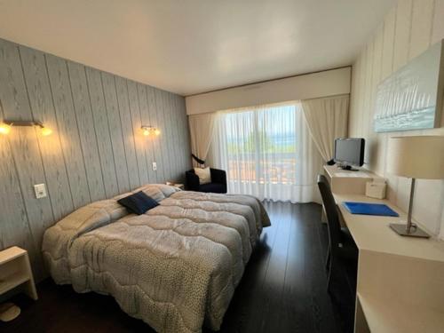 a hotel room with a bed and a desk with a television at Hôtel Restaurant le Panorama in Évian-les-Bains