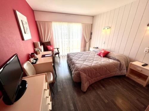 a hotel room with a bed and a television at Hôtel Restaurant le Panorama in Évian-les-Bains