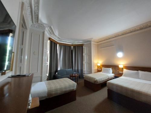 a hotel room with two beds and a chair at Edinburgh House Hotel in Edinburgh
