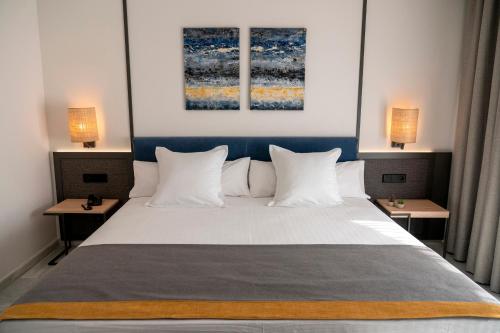 a bedroom with a large bed with two tables at URH Sitges Playa in Sitges