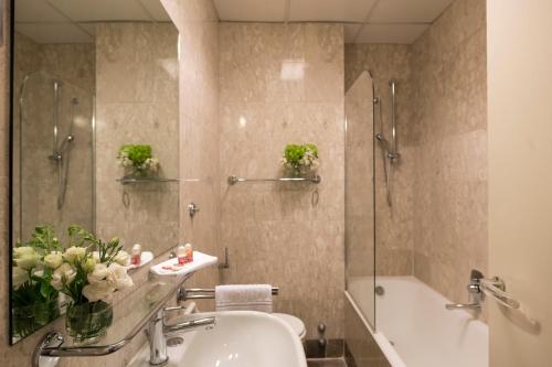 a bathroom with a sink and a shower and a tub at Bettoja Hotel Atlantico in Rome