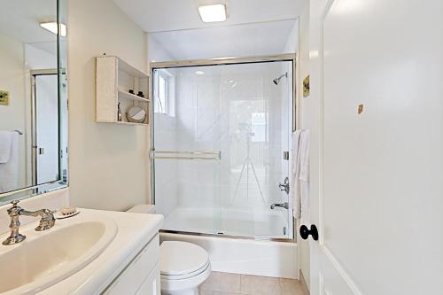 baño blanco con ducha y lavamanos en Cheery Retreat, en Newport Beach