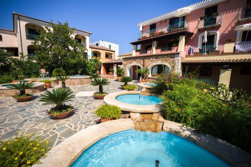 a swimming pool in a courtyard with a building at Nicolaus Club Torre Moresca in Cala Liberotto