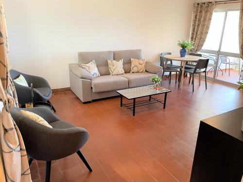 un salon avec un canapé, des chaises et une table dans l'établissement Apartamento vista mar e pôr do Sol (1,6km Praia), à Aljezur