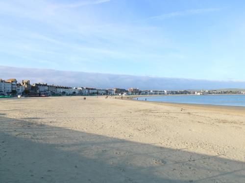 a sandy beach with people in the water and buildings at Park Mews in Weymouth