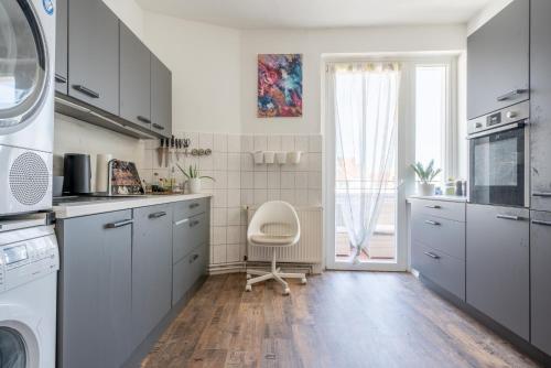 eine Küche mit grauen Schränken und einem weißen Stuhl in der Unterkunft Private Apartment in Hannover