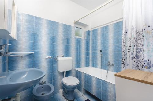 ein blau gefliestes Bad mit WC und Waschbecken in der Unterkunft Apartments and Room Lotus in Tribunj
