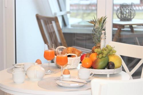 a table with a bowl of fruit and glasses of orange juice at KranichSuite - Zingst in Zingst