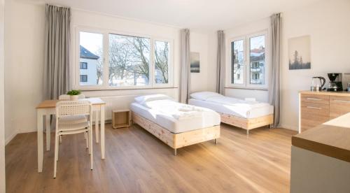 a bedroom with two beds and a table with a desk at T&K Apartments - Studio Apartments - 22 min MESSE DUS & Airport DUS in Krefeld
