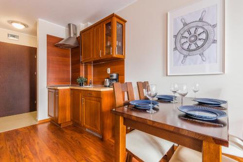 a dining room with a table and a kitchen at Flatbook Apartamenty - Port Stegna in Stegna