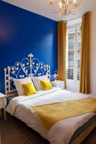 - une chambre bleue avec un lit blanc et des oreillers jaunes dans l'établissement Lovely apartment with terrace Nice centre, à Nice
