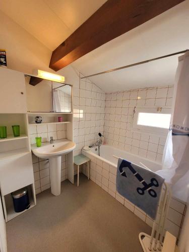 une salle de bain avec un lavabo et une baignoire et un lavabo dans l'établissement Douceur Océanne, à Mimizan