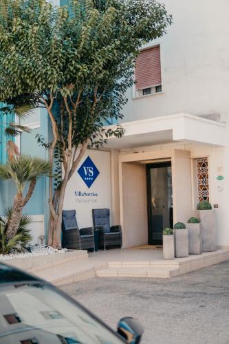 a building with chairs in front of a building at Hotel Villa Sorriso in Lido di Jesolo