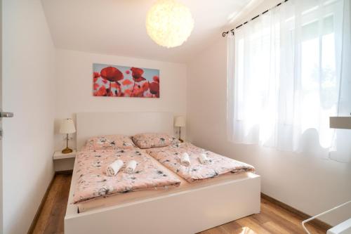 ein weißes Schlafzimmer mit einem Bett in einem Zimmer in der Unterkunft Pipacs Apartmanház in Harkány