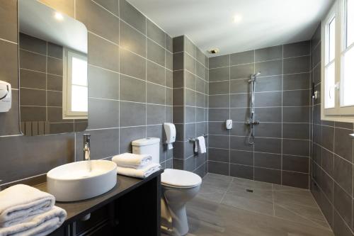 a bathroom with a sink and a toilet and a shower at Hôtel De Brunville & Spa in Bayeux