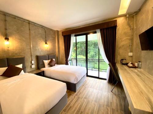 a hotel room with two beds and a window at บ้านต้นไม้โฮมสเตย์อุทัยธานี in Uthai Thani