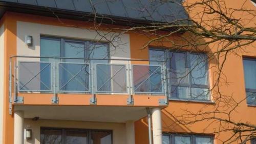 an orange and white building with a balcony at Fewo Duenengras_HERR in Ostseebad Karlshagen