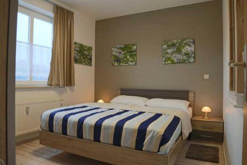 um quarto com uma cama com um cobertor listrado azul e branco em Fewo De luette Moew_KOC em Ostseebad Karlshagen
