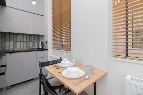 a kitchen with a wooden table with plates and bowls on it at Nad Motlawa Apartamenty Seredynskiego by Renters in Gdańsk