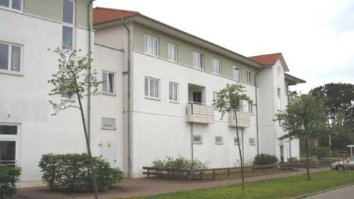 um grande edifício branco com bancos em frente em Fewo De luette Moew_KOC em Ostseebad Karlshagen