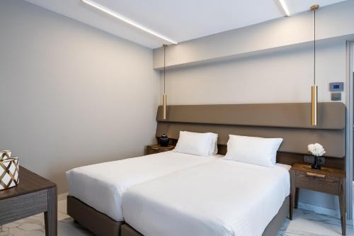 a bedroom with two white beds and two tables at Porto Platanias Beach Luxury Selection - Adults Only in Plataniás