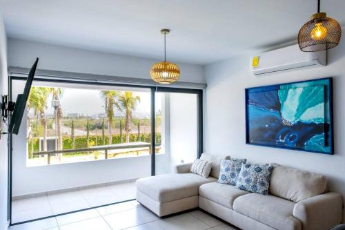 a living room with a couch and a large window at Familiar Departamento Cerca de la Playa in Mazatlán