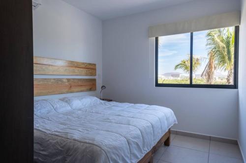 a bedroom with a bed and a window with a palm tree at Familiar Departamento Cerca de la Playa in Mazatlán